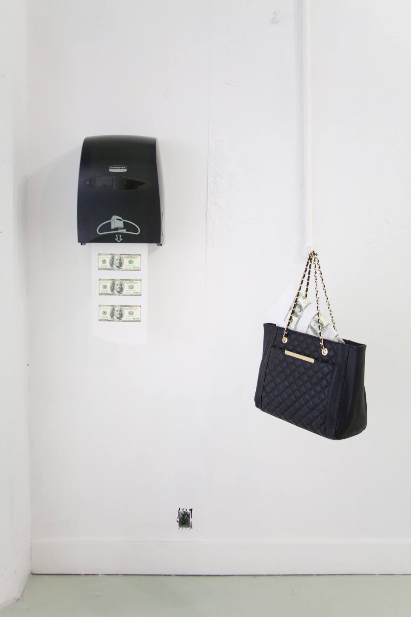 Image of a paper towel with three $100 bills glued to it coming out of a dispenser hung on a wall with a floating black purse full of paper towels with money on it in a room with white walls